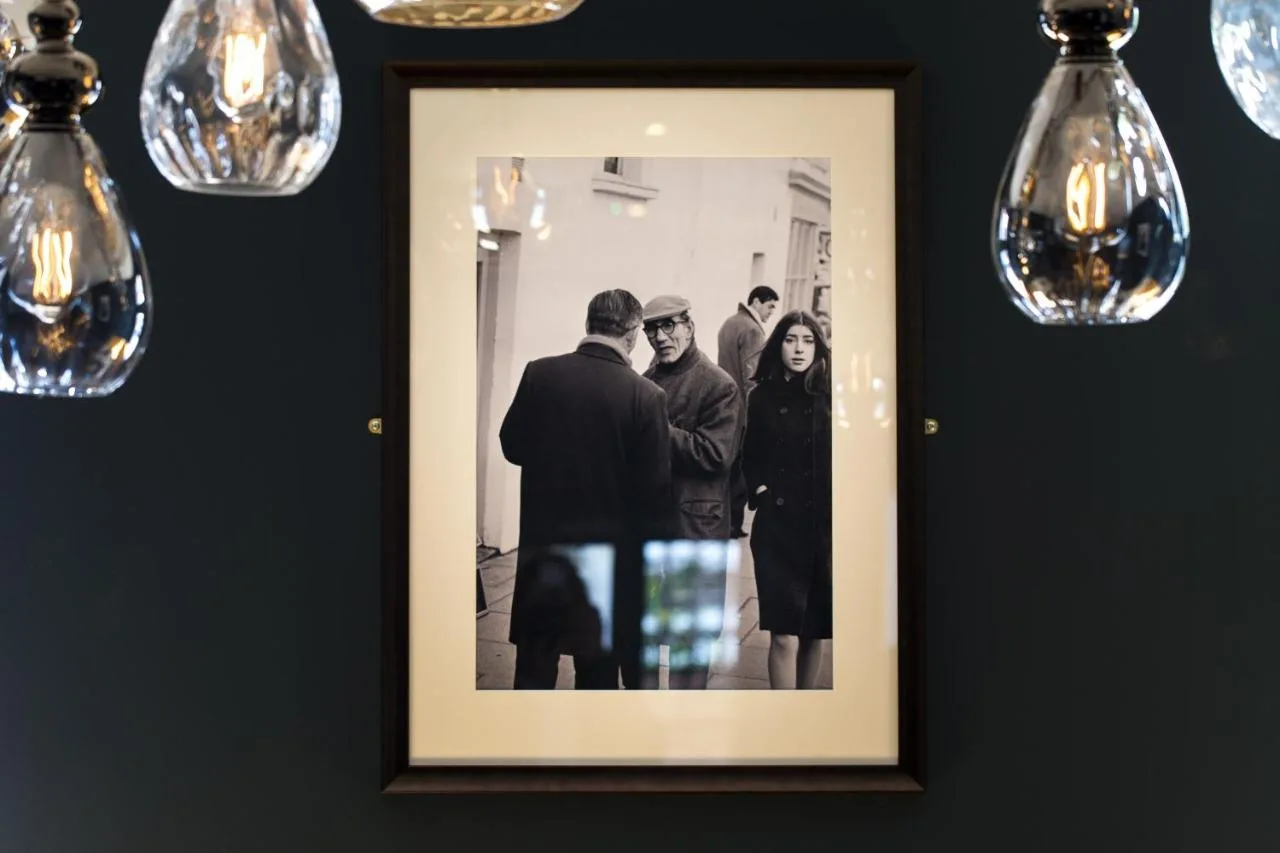 a framed picture of a group of people on a wall with lights at The Porterhouse Grill and Rooms in Oxford