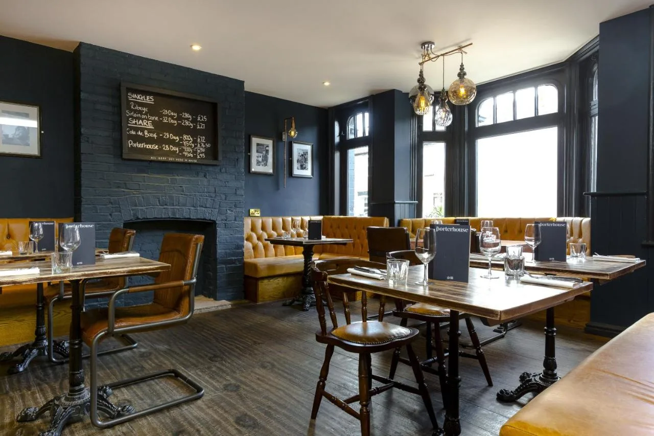 a restaurant with tables and chairs and a fireplace at The Porterhouse Grill and Rooms in Oxford